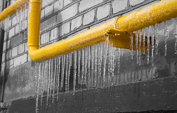 Icicles forming on a frozen yellow pipeline during extreme cold weather, highlighting the need for freeze protection solutions.