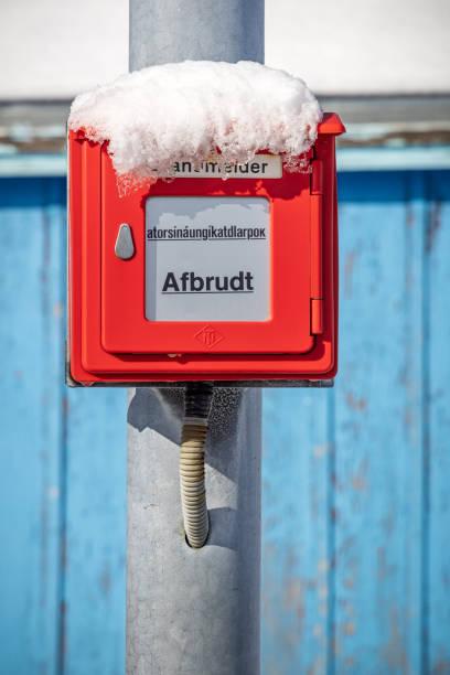 Snow-covered emergency switch on a pole in a cold outdoor environment, highlighting the need for freeze protection solutions.