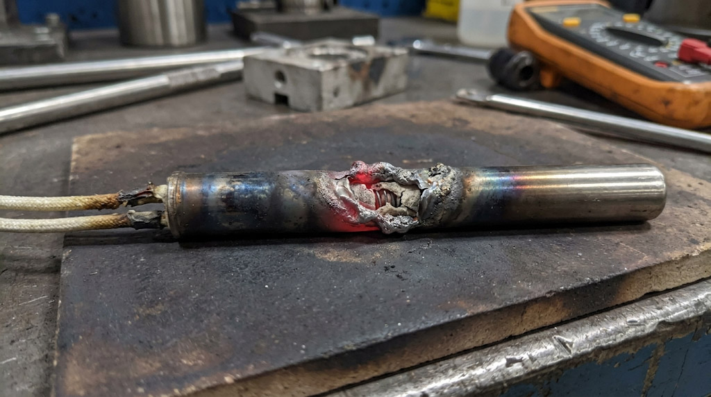 Burnt cartridge heater from static air application showing red-hot meltdown due to excessive power density